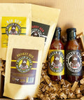 Miller & Son BBQ sauce and rub seasoning products arranged in a gift box with shredded paper filler. The set includes two bottles of sauce with yellow and black labels and three bags of rub seasoning in tan packaging with yellow and dark brown labels.