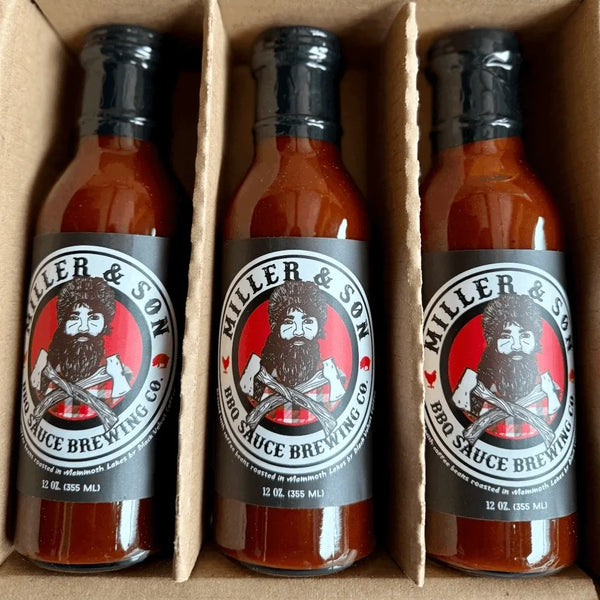 Three bottles of Miller & Son BBQ Sauce Brewing Co. hot sauce arranged in a cardboard tray.