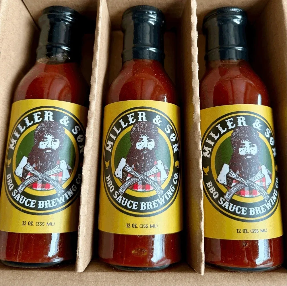 Three bottles of Miller & Son BBQ Sauce Brewing Co. hot sauce arranged in a cardboard box.