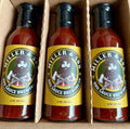 Three bottles of Miller & Son BBQ Sauce Brewing Co. hot sauce arranged in a cardboard box.