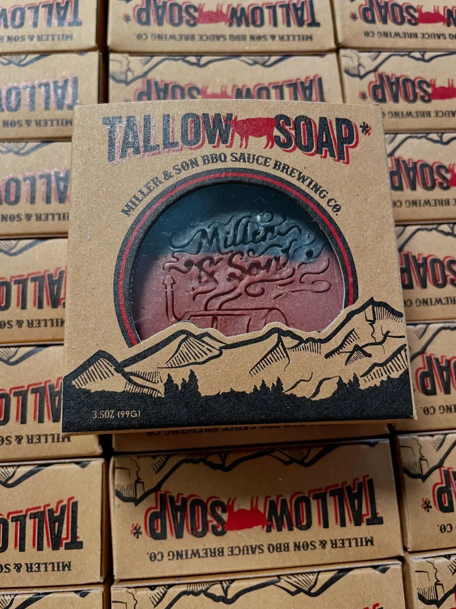 A boxed bar of Tallow Soap by Miller & Son BBQ Sauce Brewing Co. The kraft paper box features a circular cutout showing the soap inside, which has a pink-to-purple gradient with a mountain illustration on the front.